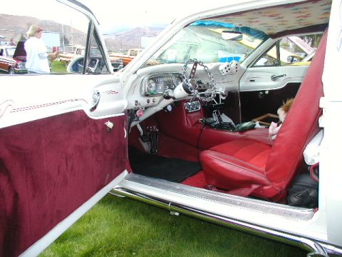 1967 Ford Ranchero - The interior of a vintage car features red upholstery, a chain-wrapped steering wheel, and fuzzy dice.
