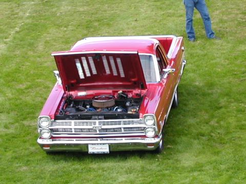 1967 Ford Ranchero - Red 1967 Ford Ranchero parked on grass with hood open, revealing the engine bay.