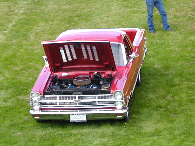 Red Ford Ranchero on grass with hood open showing V8 engine and Ranchero front plate