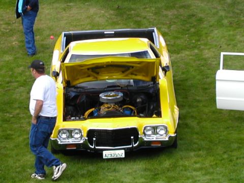 1967 Ford Ranchero - A yellow pickup truck is displayed with its hood open, revealing the engine compartment.