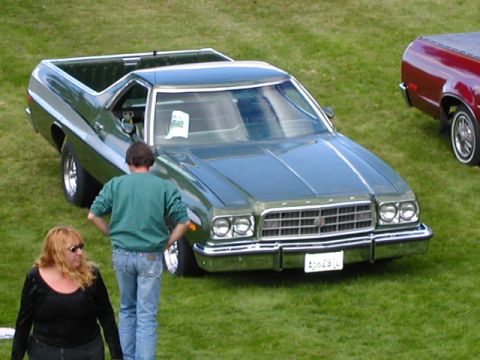 1967 Ford Ranchero - A green Ford Ranchero is parked on a grassy field next to another vehicle, with two people standing nearby.