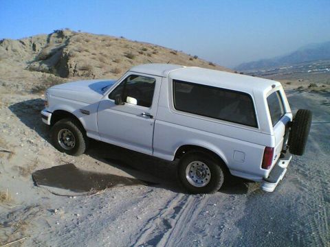 1996 Ford Bronco - 1996 Ford Bronco parked off-road in a desert landscape.