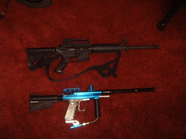 Black rifle and blue paintball gun on red carpet. Text reads SUPERMOTORS