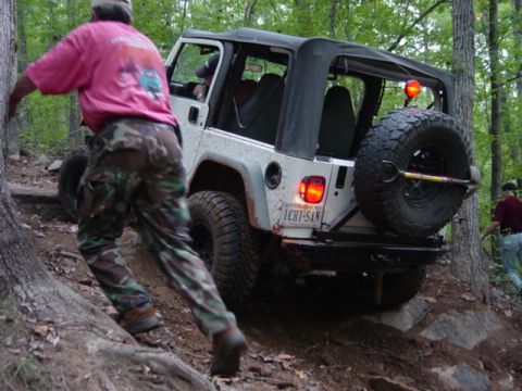 1991 Ford Bronco - A Jeep Wrangler navigates a challenging off-road course with assistance from a spotter.