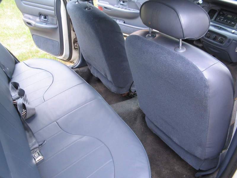 Back seat and interior of a car. Shows rear bench seat, front passenger seat, and door panel