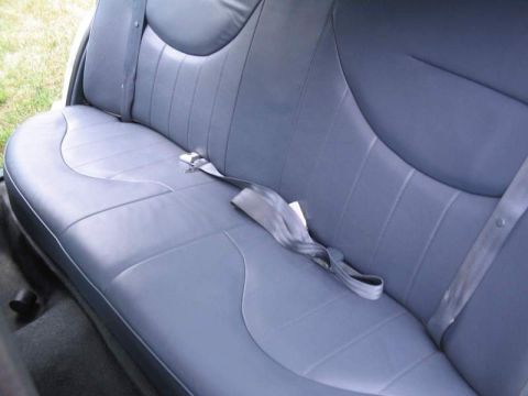 1998 Ford Crown Victoria - The interior of a vehicle shows a gray vinyl rear seat with a seatbelt.