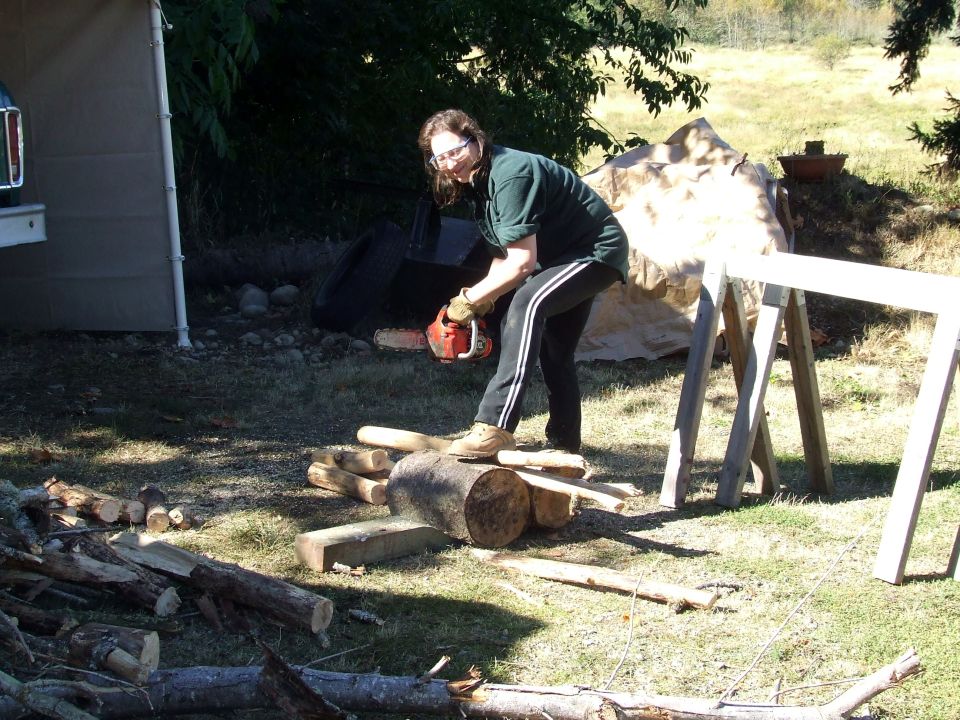 Person using a chainsaw to cut logs outdoors