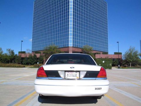 1998 Ford Crown Victoria - Rear view of a 1998 Ford Crown Victoria parked in a lot with a large glass building behind it.