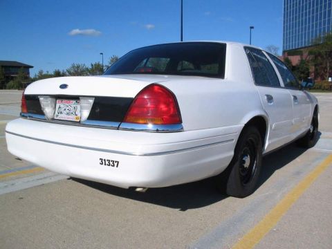 1998 Ford Crown Victoria - Rear view of a white 1998 Ford Crown Victoria sedan, a black trim panel between the taillights and the number 31337 on the rear bumper.
