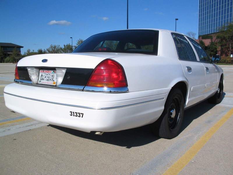 White 1998 Ford Crown Victoria sedan, rear view, with black trim panel and number 31337 on bumper