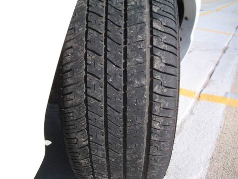 1998 Ford Crown Victoria - A close-up view of a vehicle's tire tread, with a portion of the white body visible.