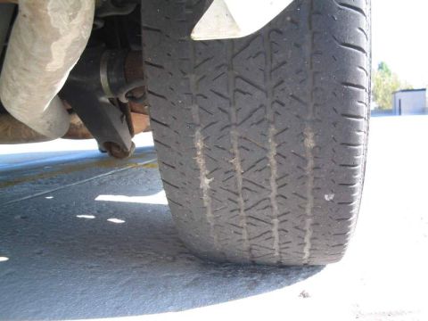 1998 Ford Crown Victoria - A close-up view of a vehicle's tire and suspension components, showing wear.