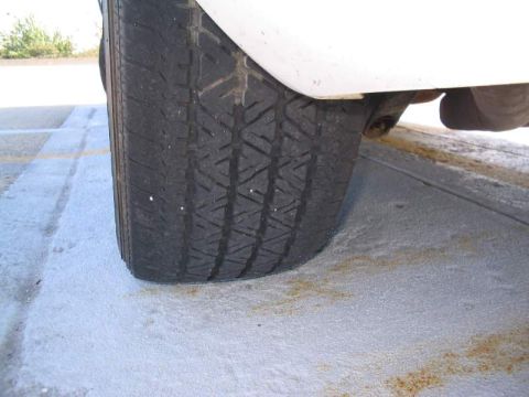 1998 Ford Crown Victoria - A close-up view of a vehicle's tire and the underside of its body panel.