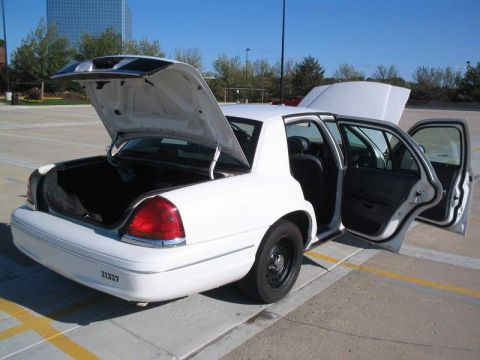 1998 Ford Crown Victoria - A white 1998 Ford Crown Victoria is shown with its trunk and doors open, revealing the interior and cargo space.