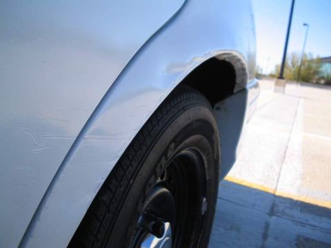 1998 Ford Crown Victoria - Close-up view of the rear wheel well of a white vehicle, showing some paint imperfections on the fender.