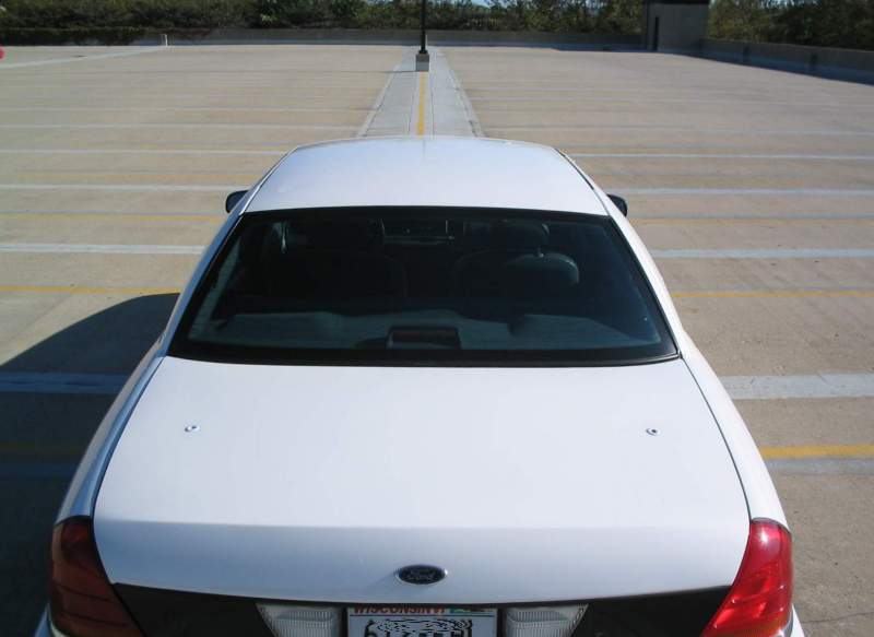 Rear view of a white sedan parked in a lot. License plate is visible
