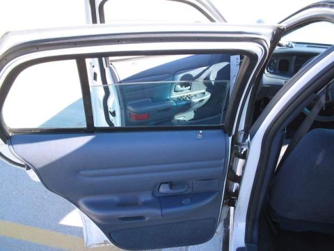 1998 Ford Crown Victoria - The interior door panel and a reflection of the dashboard are visible through the open door of a white vehicle.