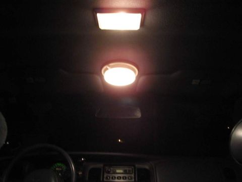 1998 Ford Crown Victoria - The interior of a vehicle is dimly lit by overhead lights, with a portion of the dashboard and steering wheel visible.