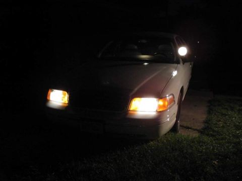 1998 Ford Crown Victoria - Front view of a 1998 Ford Crown Victoria at night with its headlights illuminated.