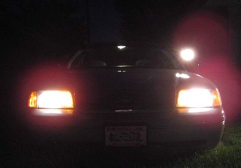 1998 Ford Crown Victoria - A car's headlights illuminate the dark, with its license plate clearly visible.