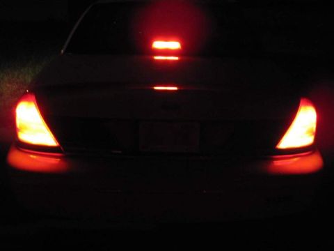 1998 Ford Crown Victoria - The rear of a 1998 Ford Crown Victoria is shown at night with its brake lights illuminated.