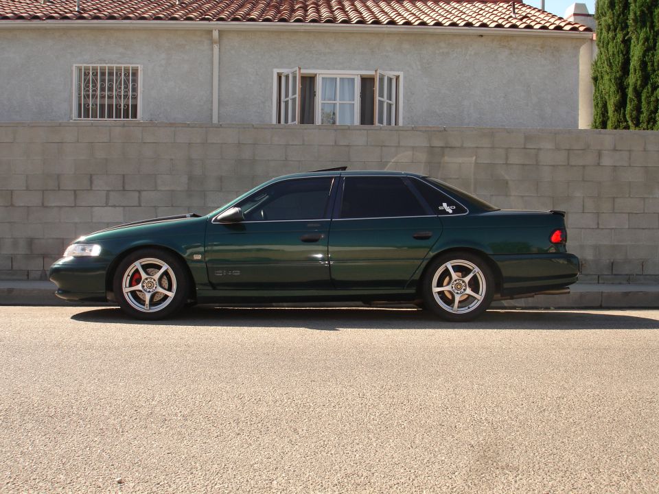 1993 Ford Taurus sedan, dark green, aftermarket wheels, parked curbside