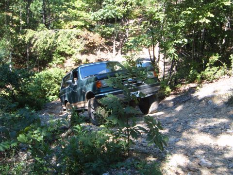 1988 Ford Bronco - This 1988 Ford Bronco navigates a rough, wooded trail, with another vehicle visible in the background.