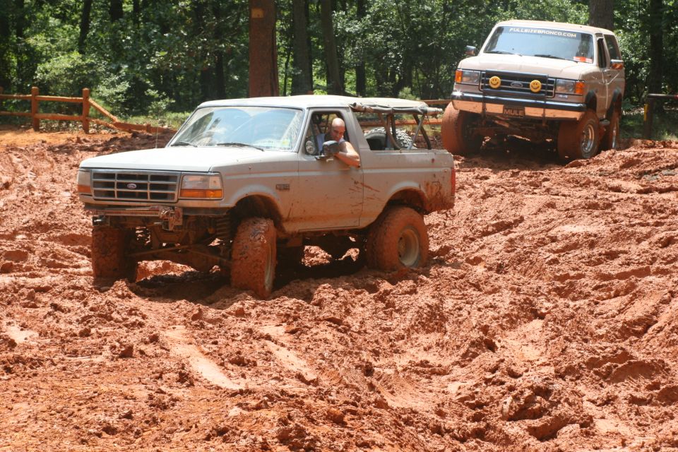 Tan Ford Bronco driving through mud, front view