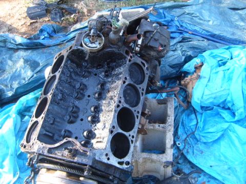 1988 Ford Bronco - A disassembled engine block and associated parts are visible, resting on a blue tarp outdoors.