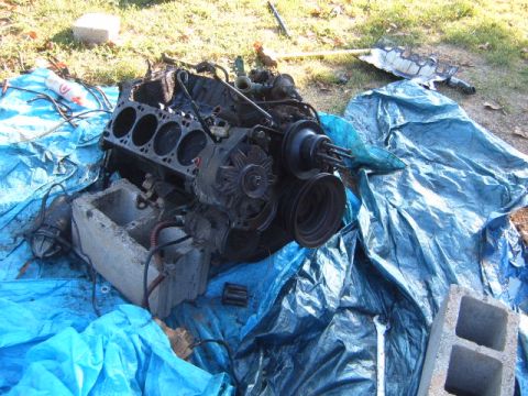 1988 Ford Bronco - Engine block with cylinders exposed, resting on a blue tarp with concrete blocks.