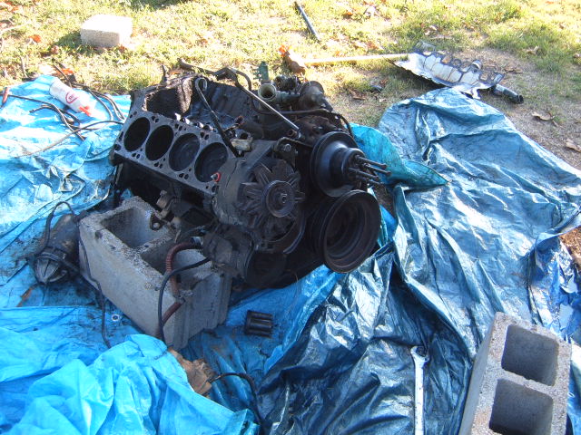 Engine block with cylinders exposed, resting on a blue tarp