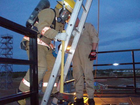 1981 Ford Bronco - Firefighters practice using a ladder and axe during training exercises at dusk.