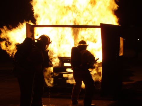 1981 Ford Bronco - Firefighters train in front of a burning structure, practicing their response to a fire.