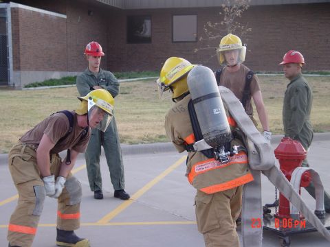 1981 Ford Bronco - Several individuals in firefighter gear are gathered around a fire hydrant, appearing to practice hose deployment.