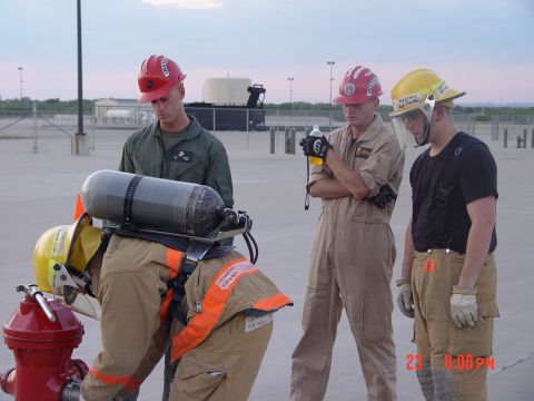1981 Ford Bronco - Four individuals in firefighter gear and helmets are gathered around a red fire hydrant, seemingly during a training exercise.