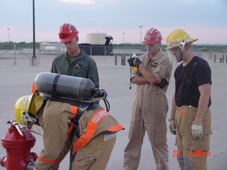 Firefighters in protective gear and helmets practice with a red fire hydrant