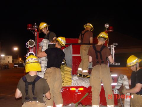 1981 Ford Bronco - Firefighters are seen working with hoses on the back of a red truck during what appears to be a training exercise at night.