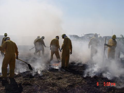 1981 Ford Bronco - Several individuals in protective gear manage a controlled fire, creating significant smoke.