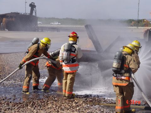 1981 Ford Bronco - Firefighters practice extinguishing a blaze during a training exercise, with water spraying over the scene.