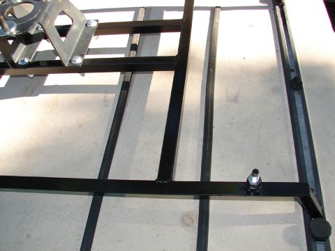 1996 Ford Bronco - A close-up view of a black metal tire carrier mount assembly.