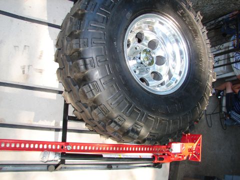 1996 Ford Bronco - A large off-road tire and a red Hi-Lift jack are shown, likely for vehicle recovery.