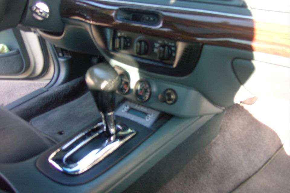 Car interior console with automatic shifter, dual gauges, and wood-grain dash trim