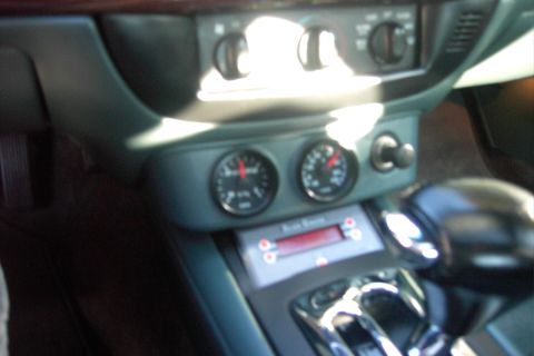 1996 Mercury Grand Marquis - The interior of a vehicle shows two gauges and a radio with a red display.