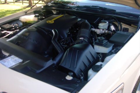 1996 Mercury Grand Marquis - Under-hood view of a V8 engine bay with a black plastic engine cover reading "V8" and a partially visible "CAUTION FAN" label, alongside a…