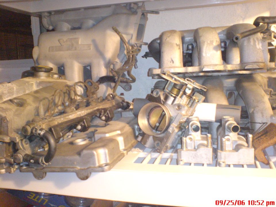 several engine intake manifolds and throttle bodies on a shelf