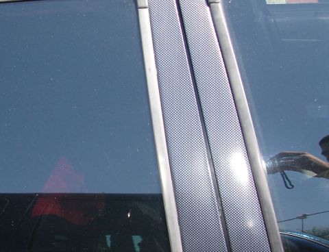 1993 Ford Taurus - Close-up of a car's side pillar, showing textured trim and a reflection in the window.