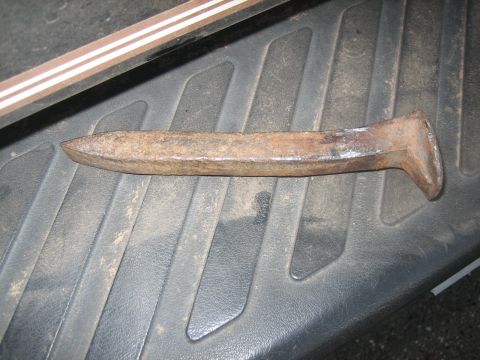 1995 Ford Bronco - A close-up view of a single, weathered railroad spike resting on a dark, ribbed surface.