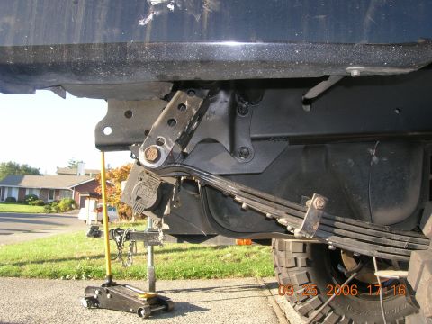 1996 Ford Bronco - Close-up view of the leaf spring suspension system, with a jack supporting the vehicle's frame.