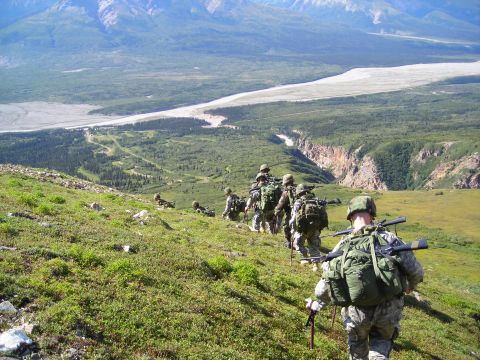 2003 Jeep TJ - A group of soldiers traverses a steep, grassy mountainside, with a vast river valley and mountains stretching out before them.