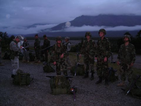 2003 Jeep TJ - Soldiers prepare for an outdoor activity with their equipment laid out, under a cloudy sky with mountains in the background.